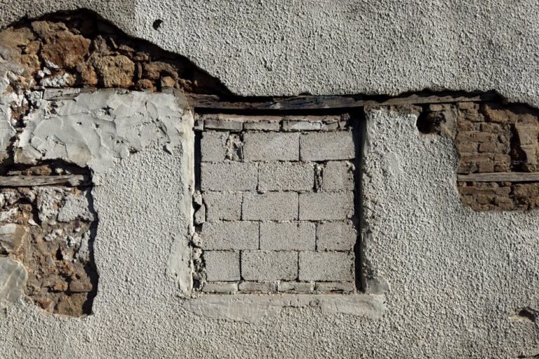 cracked building facade with bricks showing underneath